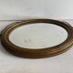 Antique oval mirror in gilded wood, bevelled mercury glass, 19th century.