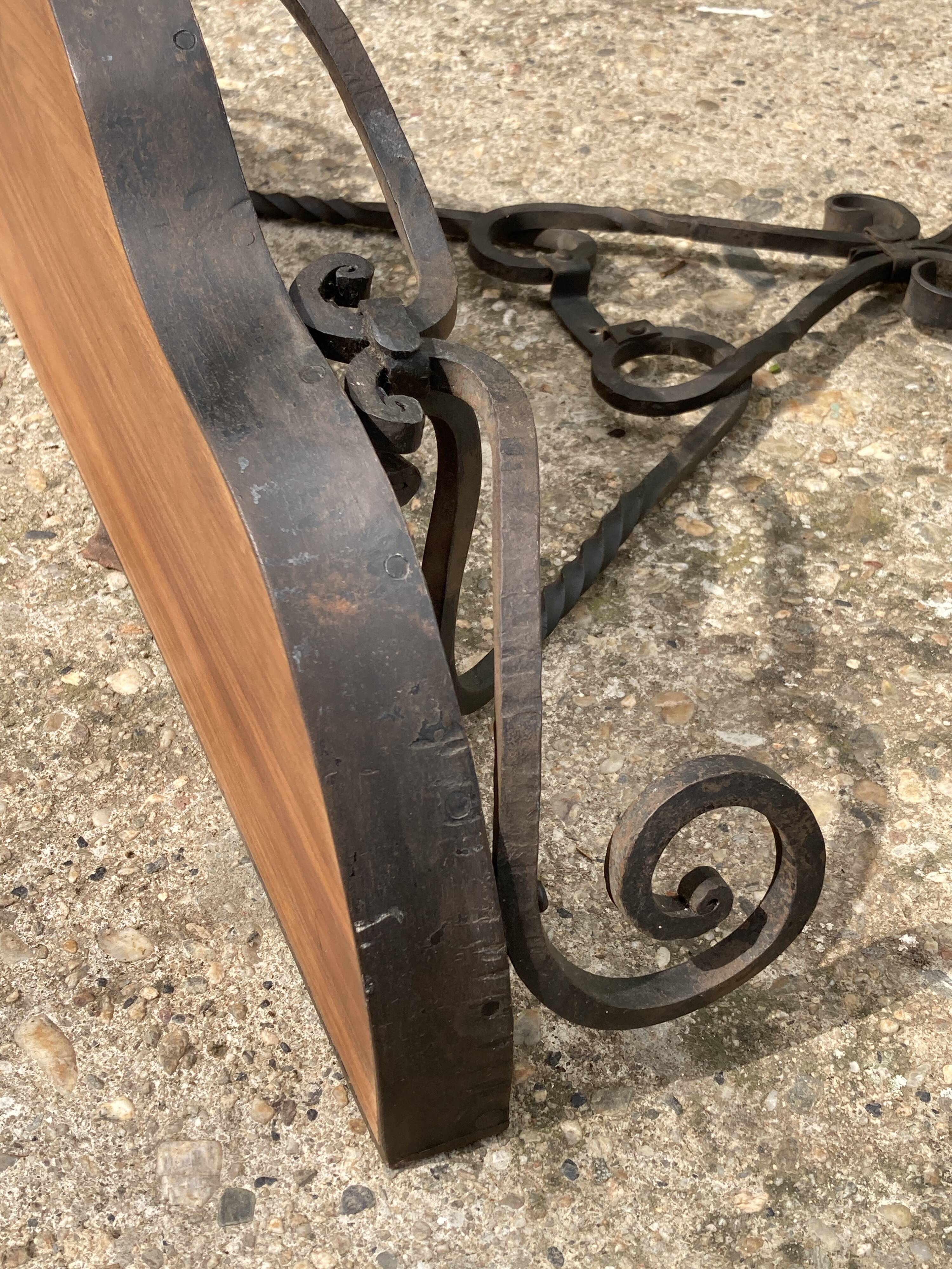Old wrought iron console with a fleur-de-lis design.