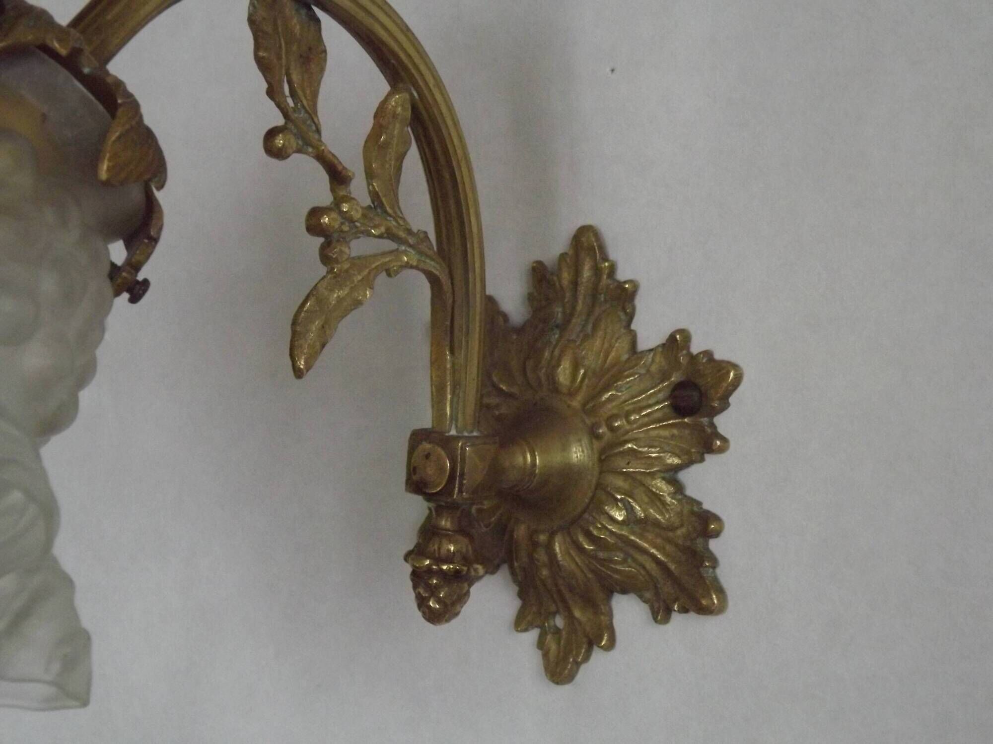 Simple wall sconce in French Art Nouveau bronze with a white glass shade featuring patterns.