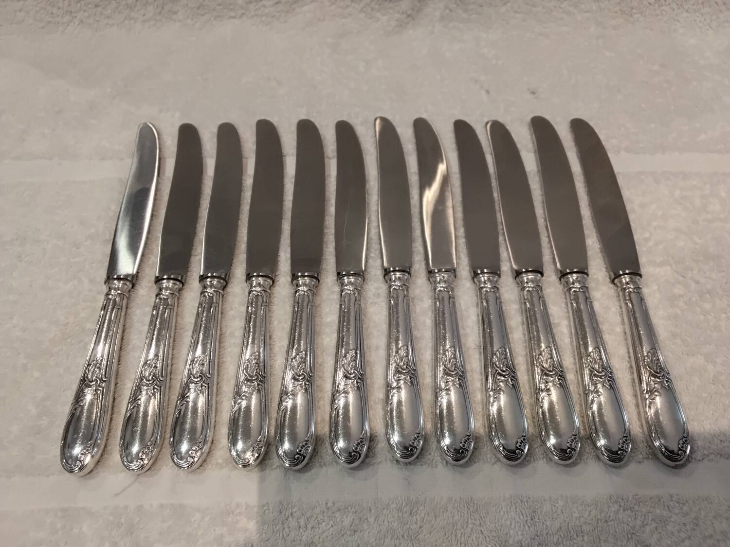 12 silver-plated metal table knives with rocaille ribbon decoration, 25.1 cm