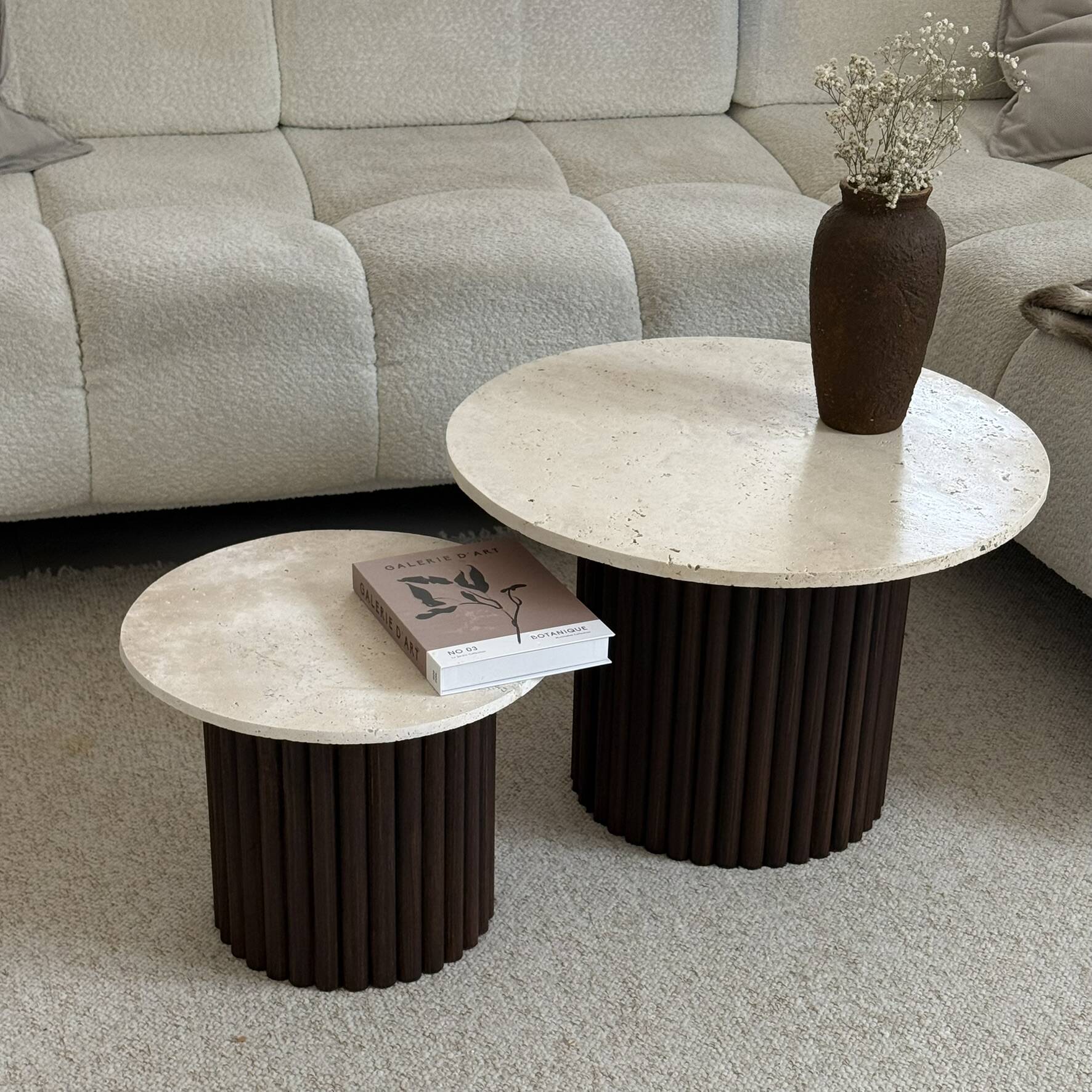 Round nesting coffee table in travertine and dark fluted wood.