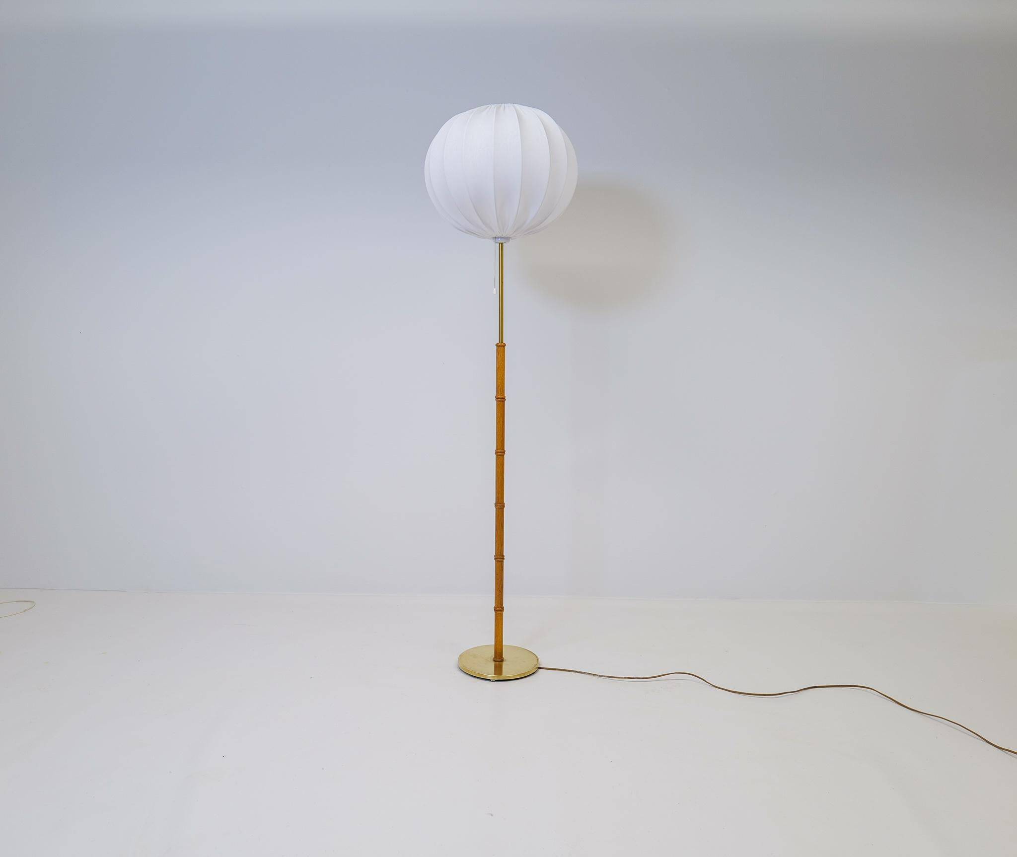 Mid-century floor lamp in brass and oak by Falkenbergs Belysning, Sweden, 1960s.
