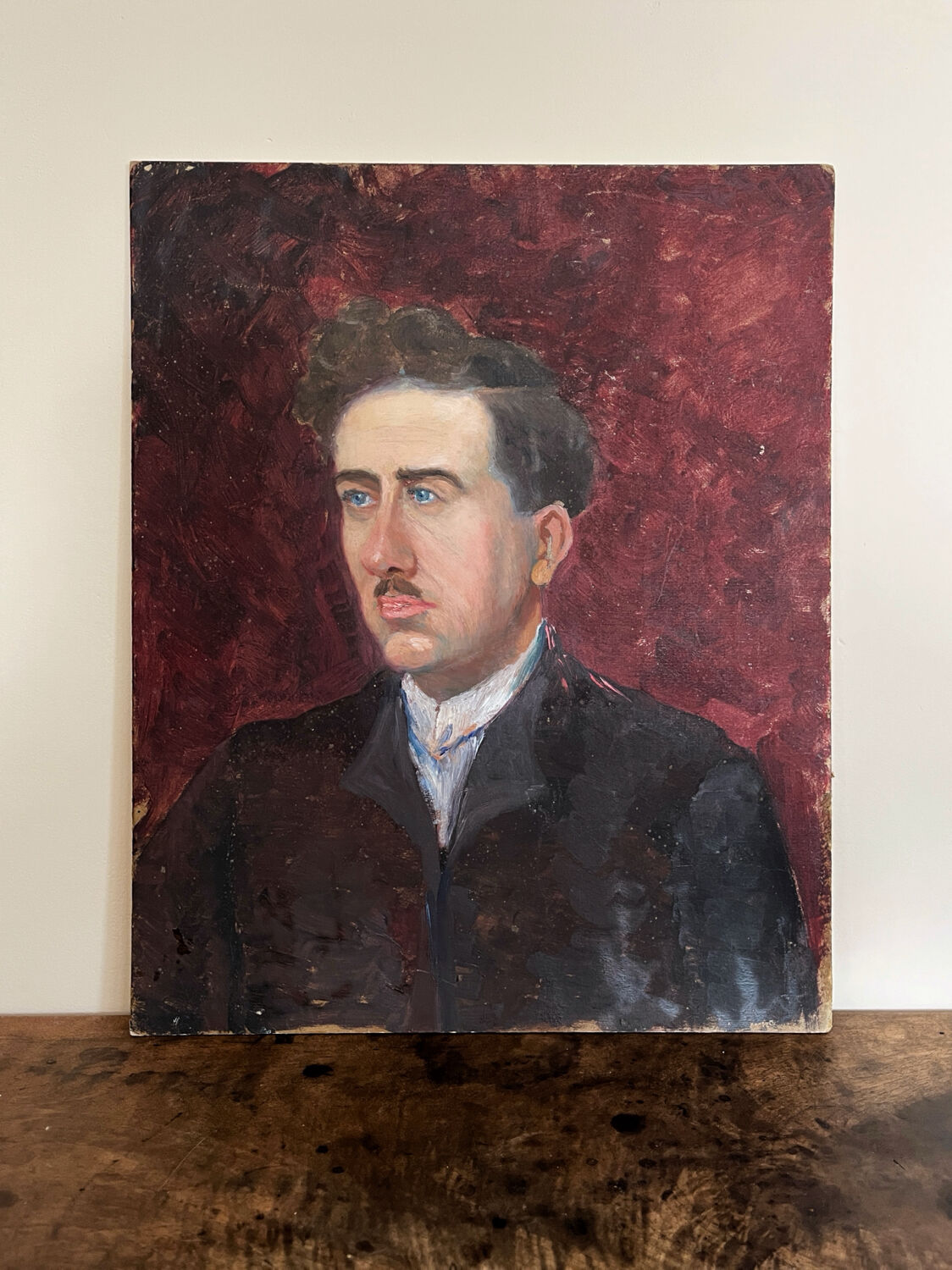 Old oil painting on cardboard portrait of a man in a dark suit