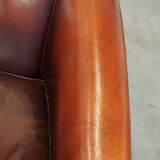 Comfortable, rugged cognac-colored sheepskin club armchair with a characteristic seat cushion