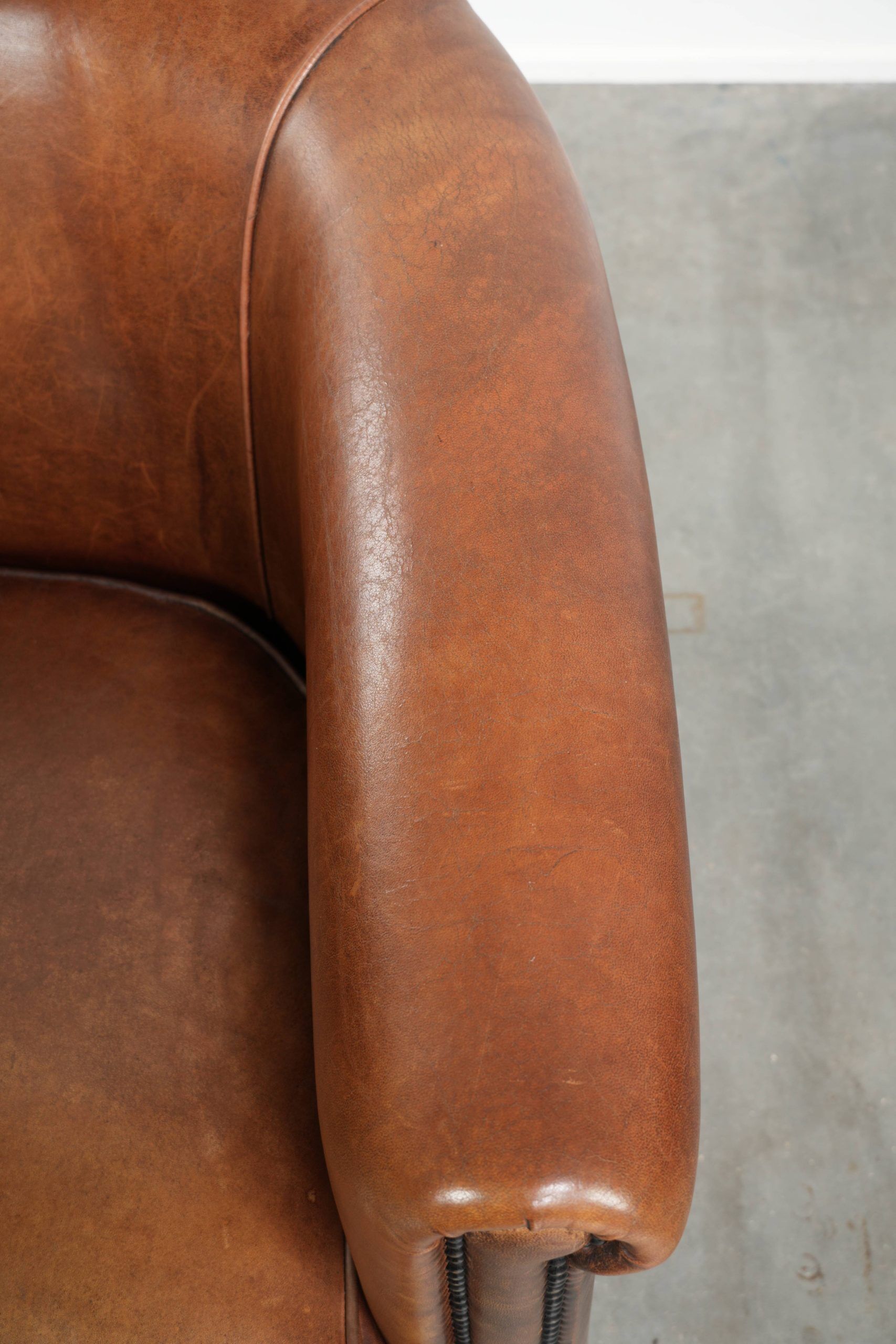 Sheepskin club armchair with a cognac colour finished with decorative nails