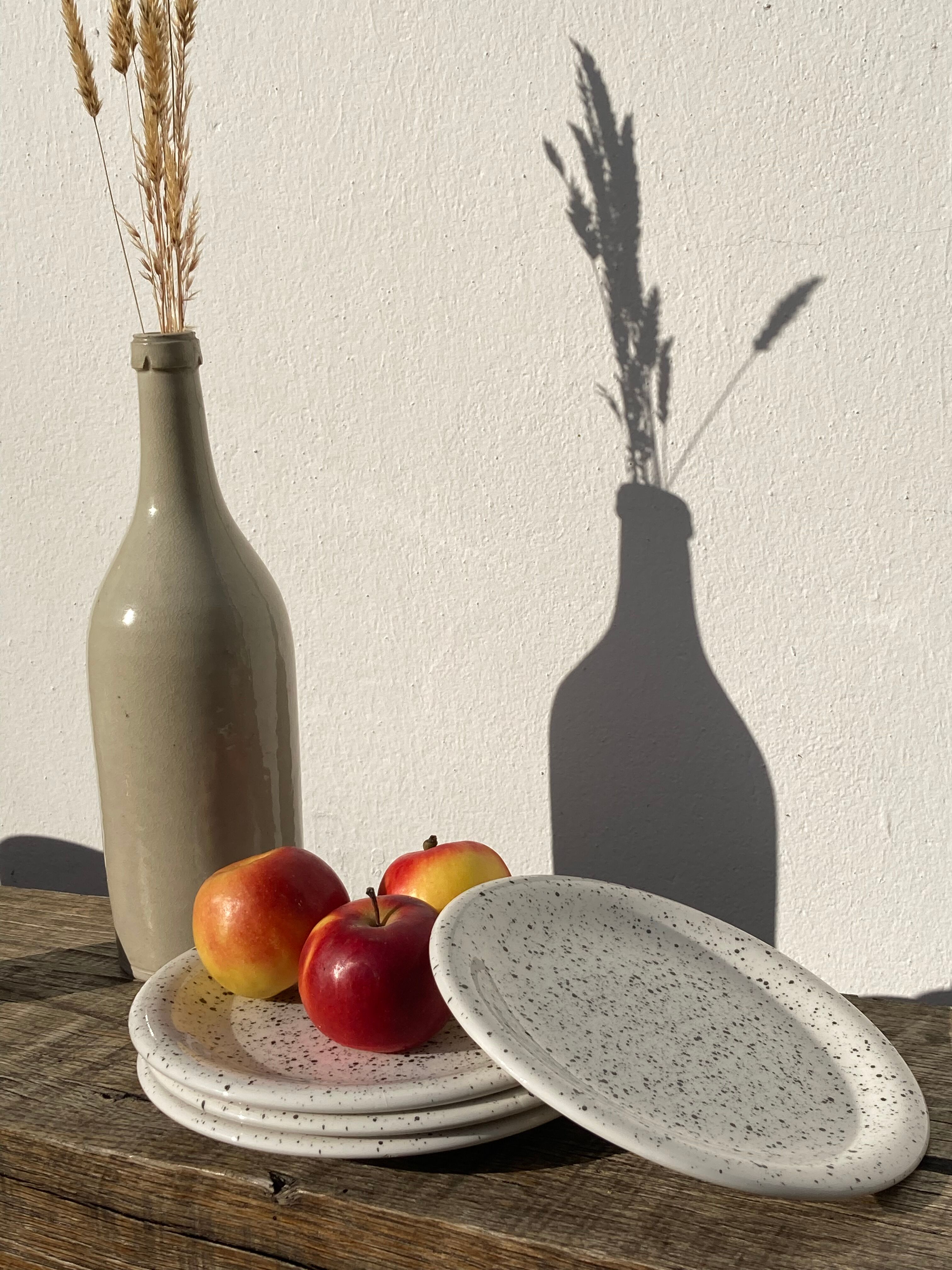 4 black speckled dessert plates on a vintage white background