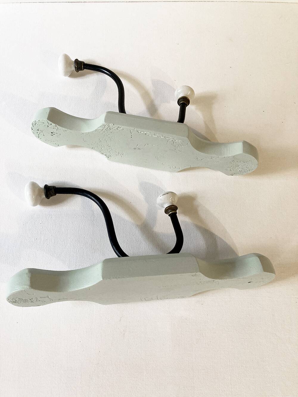 Antique metal and porcelain coat hooks, painted wooden support