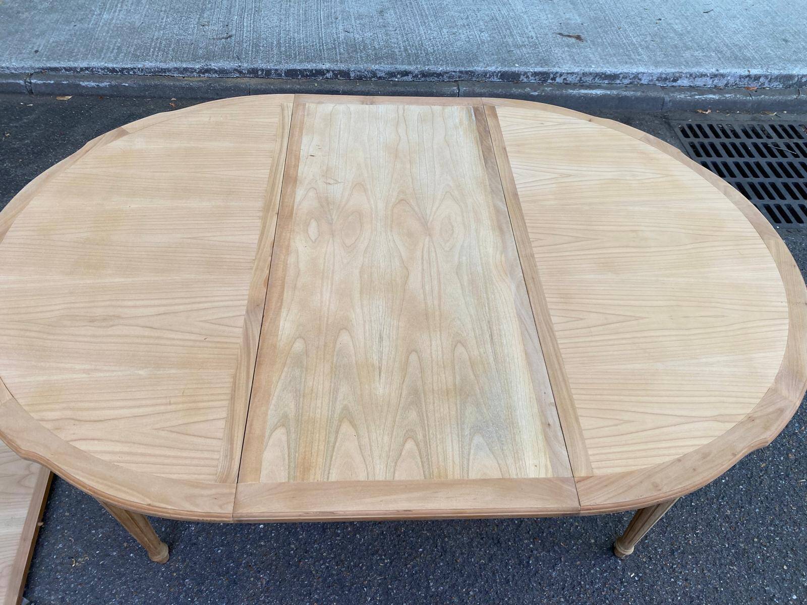 Extendable round table in renovated Louis XVI style, made of light wood, with 2 extensions.