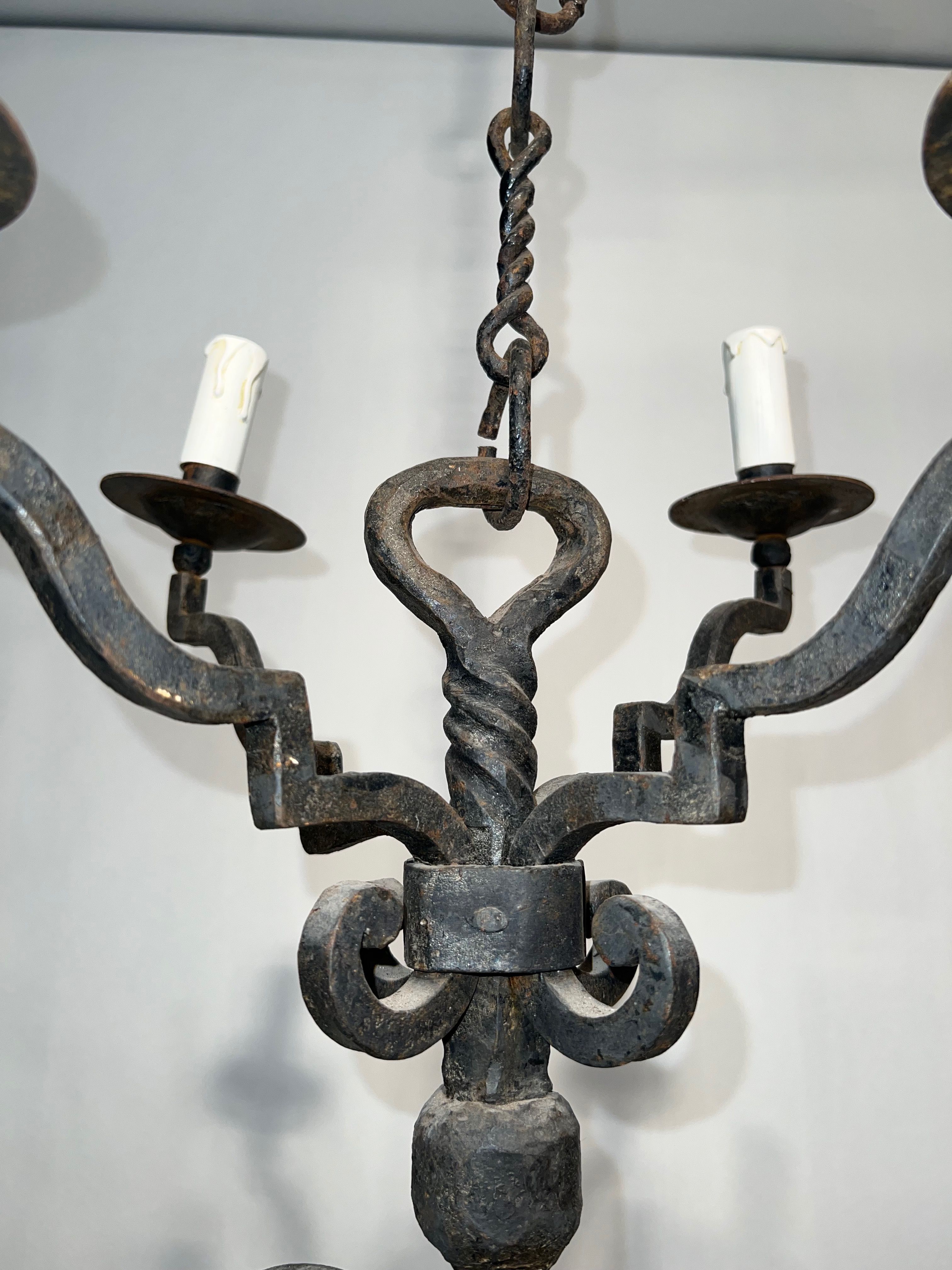 Two-tiered wrought iron chandelier with eight light arms in Gothic style.