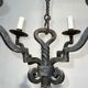 Two-tiered wrought iron chandelier with eight light arms in Gothic style.