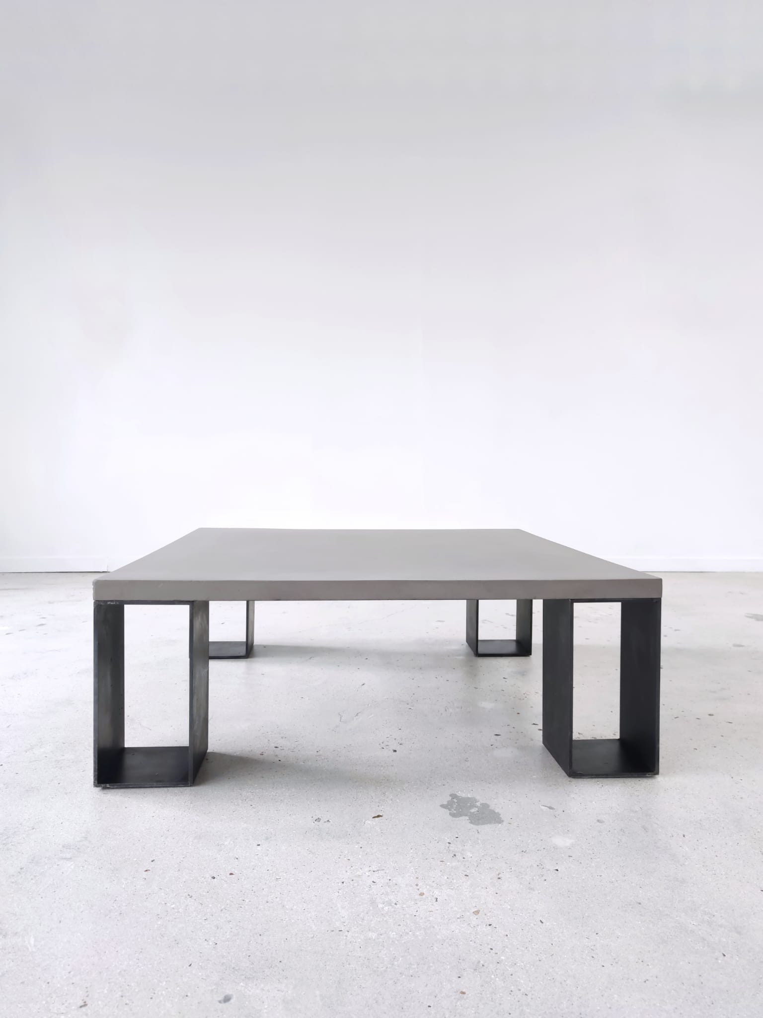 Table basse minimaliste en béton ciré et acier massif 1m20x1m20