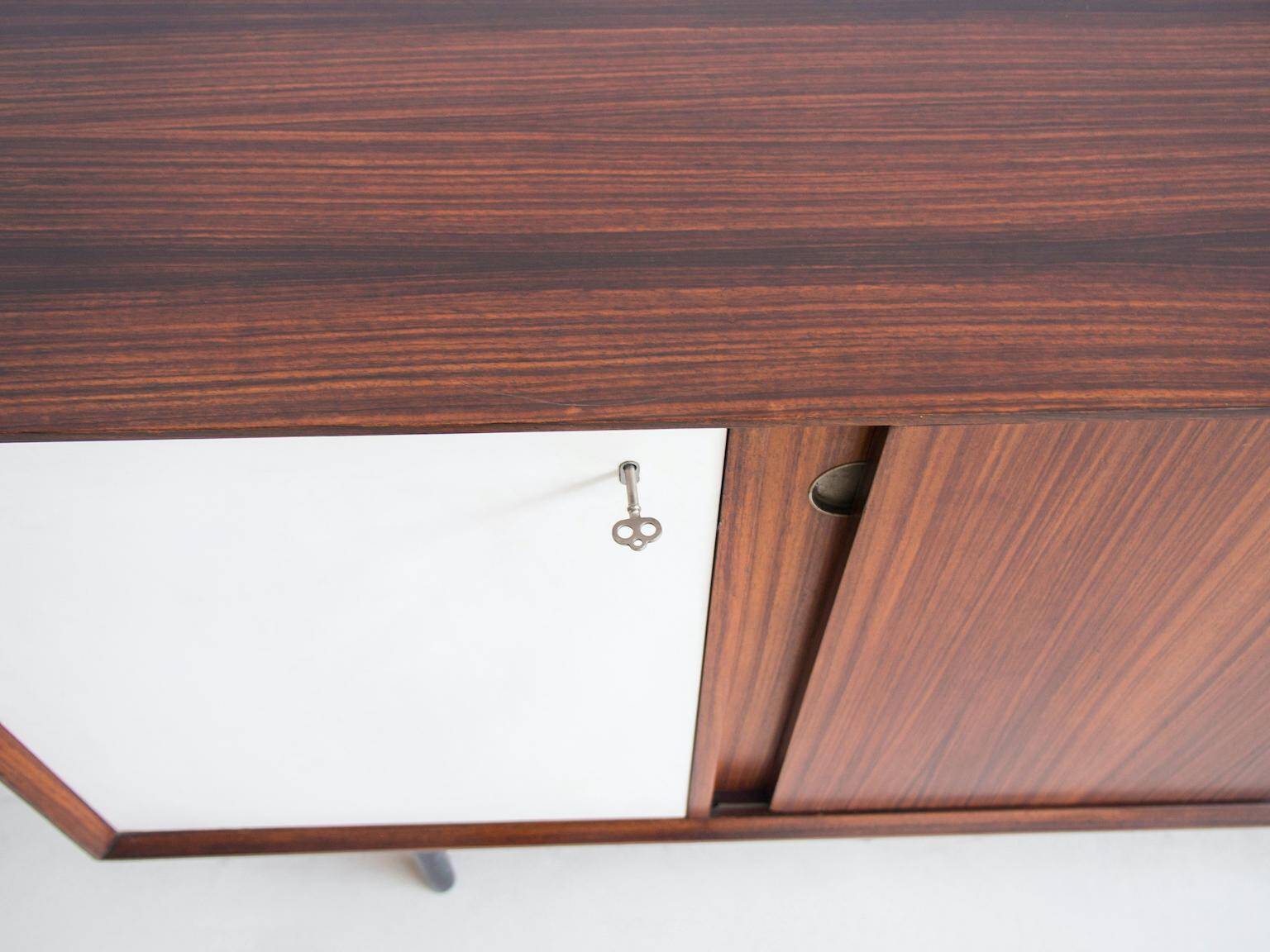 Wooden sideboard with sliding door and white drawers, around 1960.