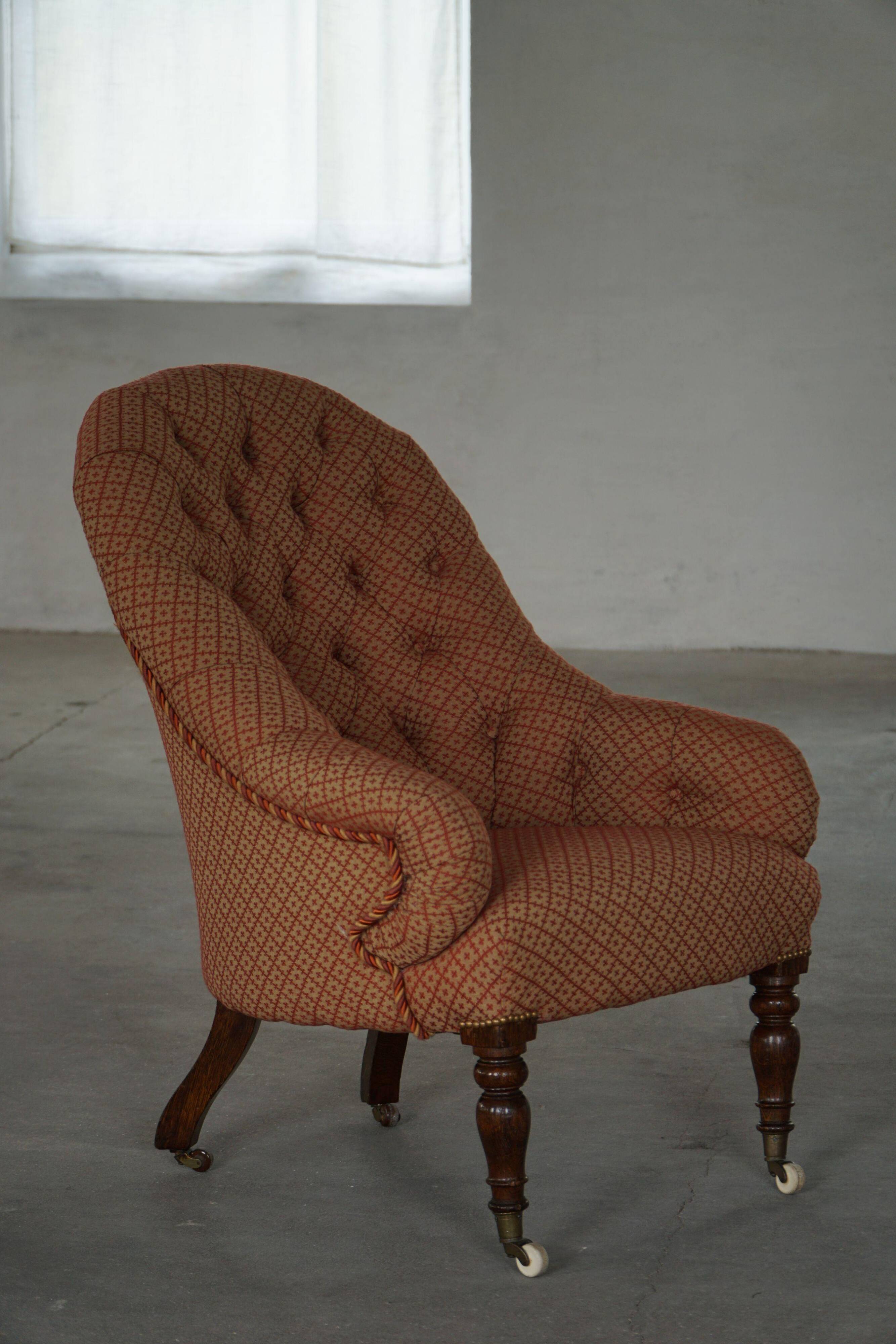 Victorian mahogany armchair, with wheels and coloured fabric, England, early 1900s.