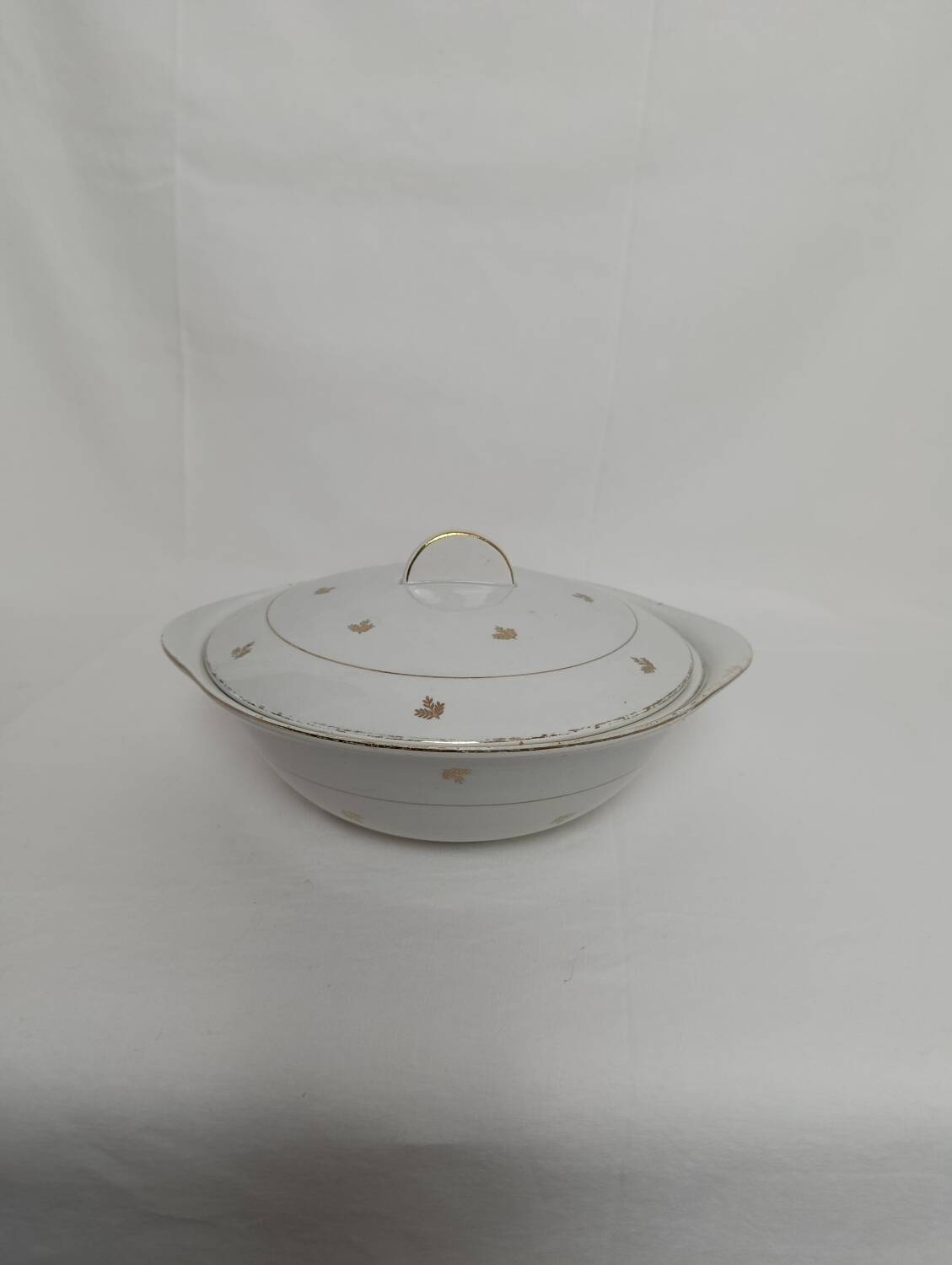 White earthenware soup tureen with a golden pattern.