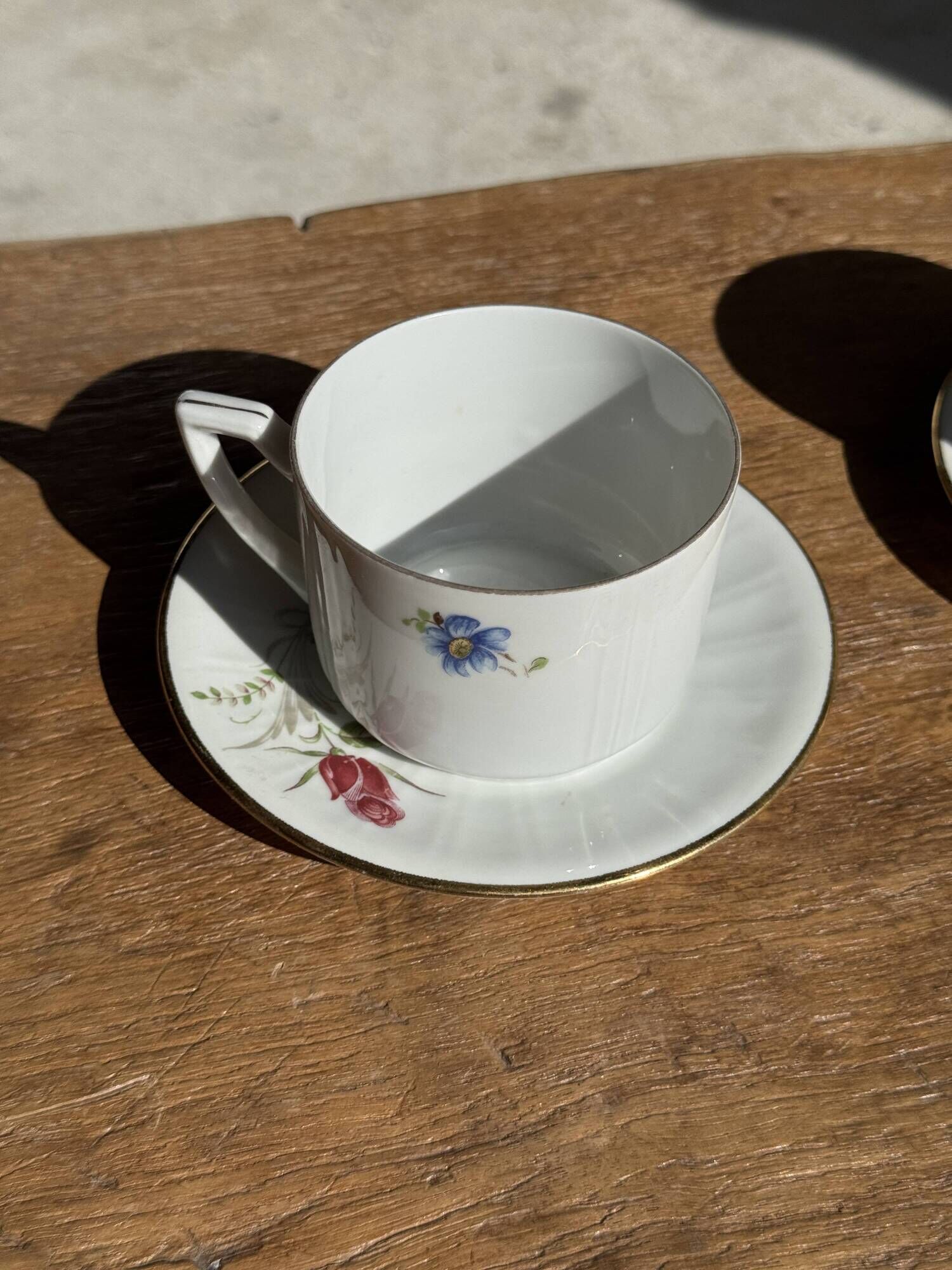 Pair of white porcelain cups from ADP France with a floral pattern and their s