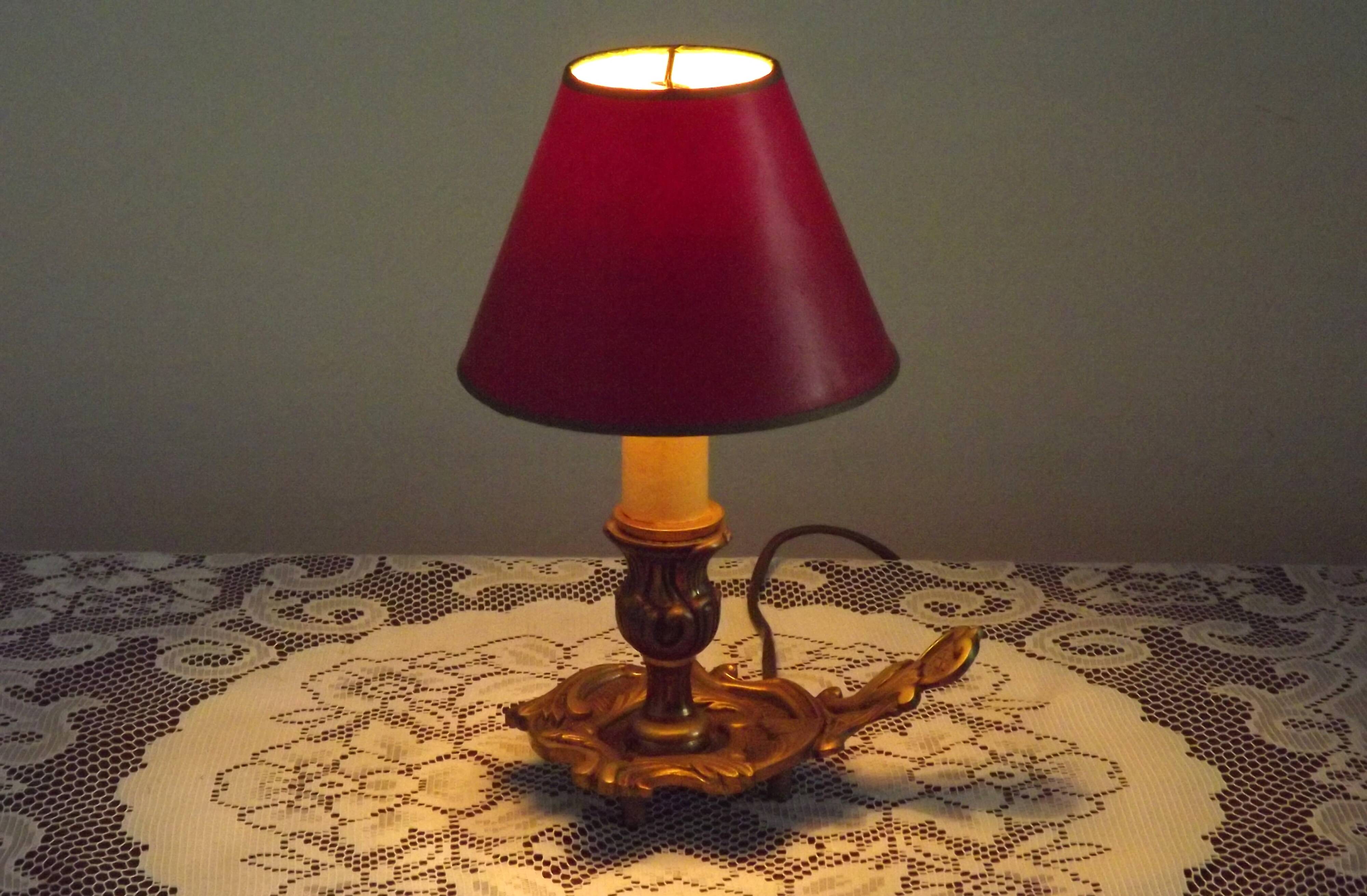 Vintage French bronze Wee Willie Winkie style lamp with red card shade.