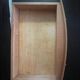 Blonde wooden doll's chest with brass handles.