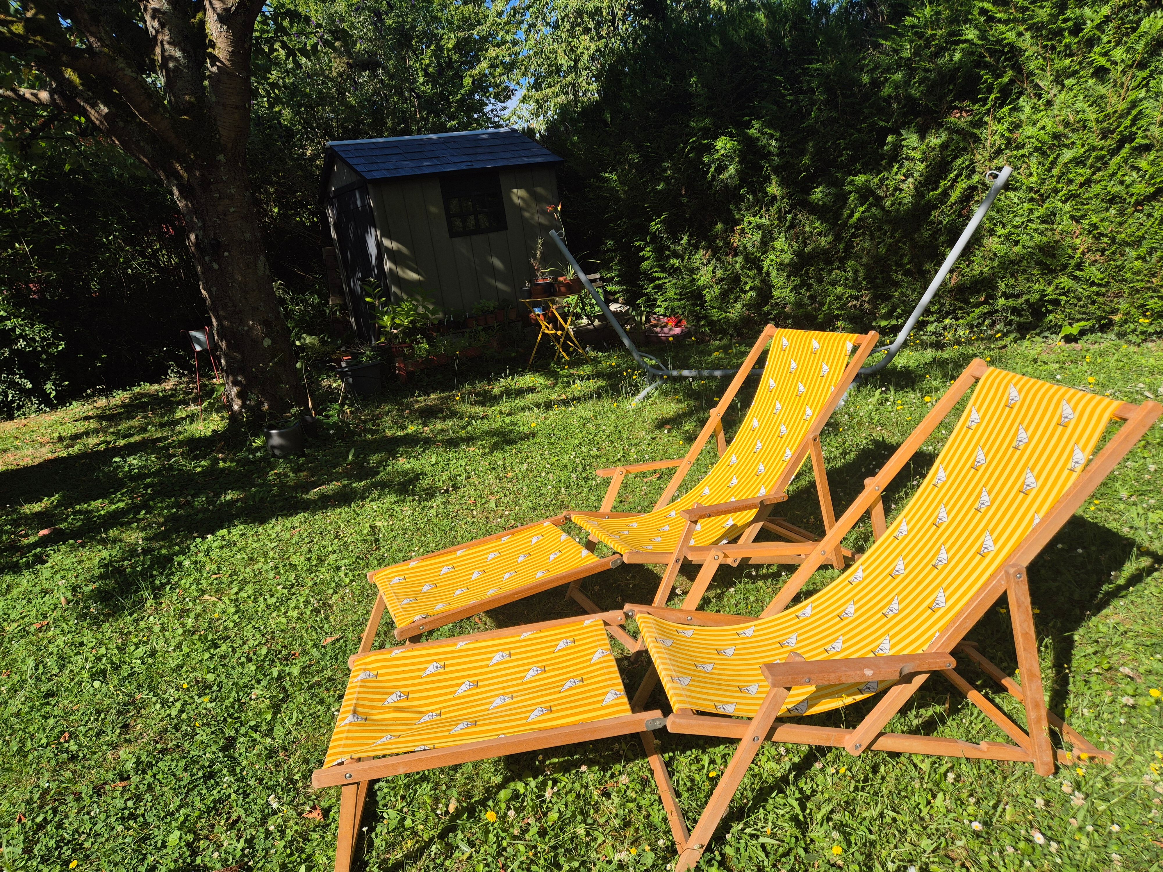 2 vintage Chilean deck chairs made of wood and yellow fabric printed with sailboats, with footrests.
