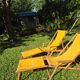 2 vintage Chilean deck chairs made of wood and yellow fabric printed with sailboats, with footrests.