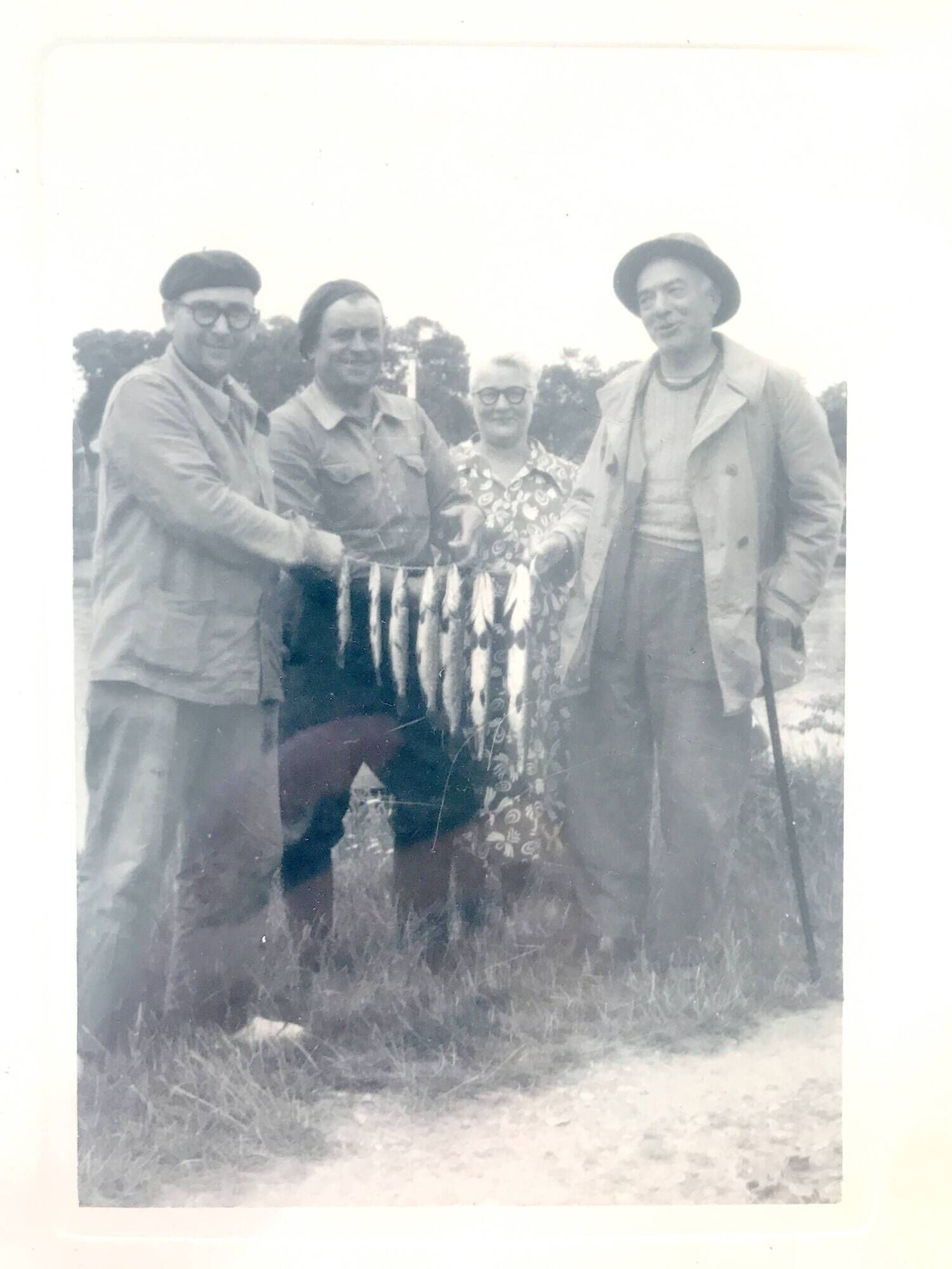 Fishing trophy with radiant faces, c. 1950. Black and white photograph.