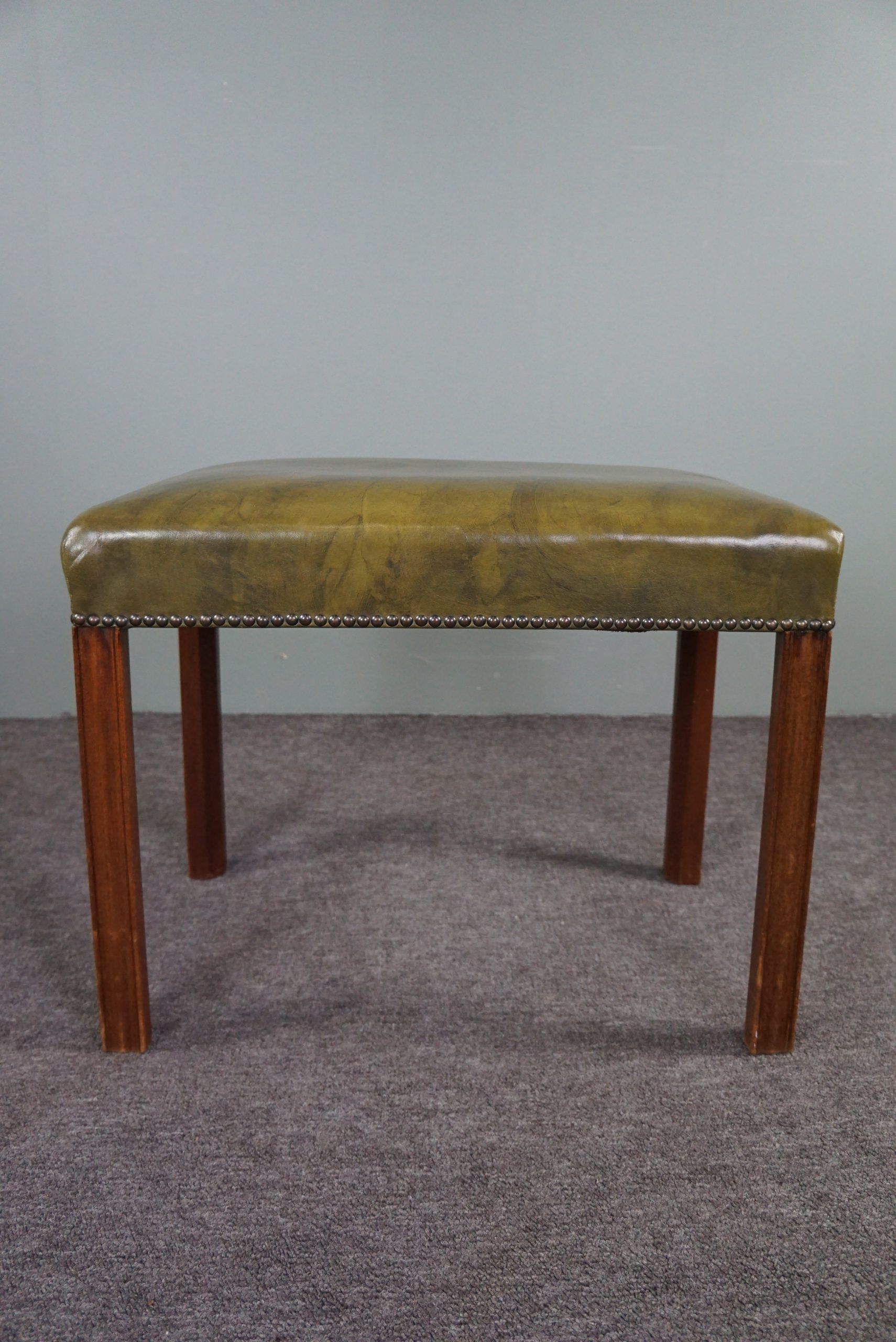 Elegant armchair and footrest in English green leather