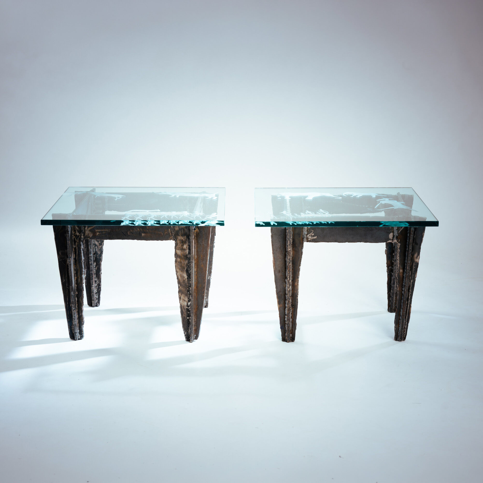 2 brutalist steel side tables with primitive  scene motifs etched glass