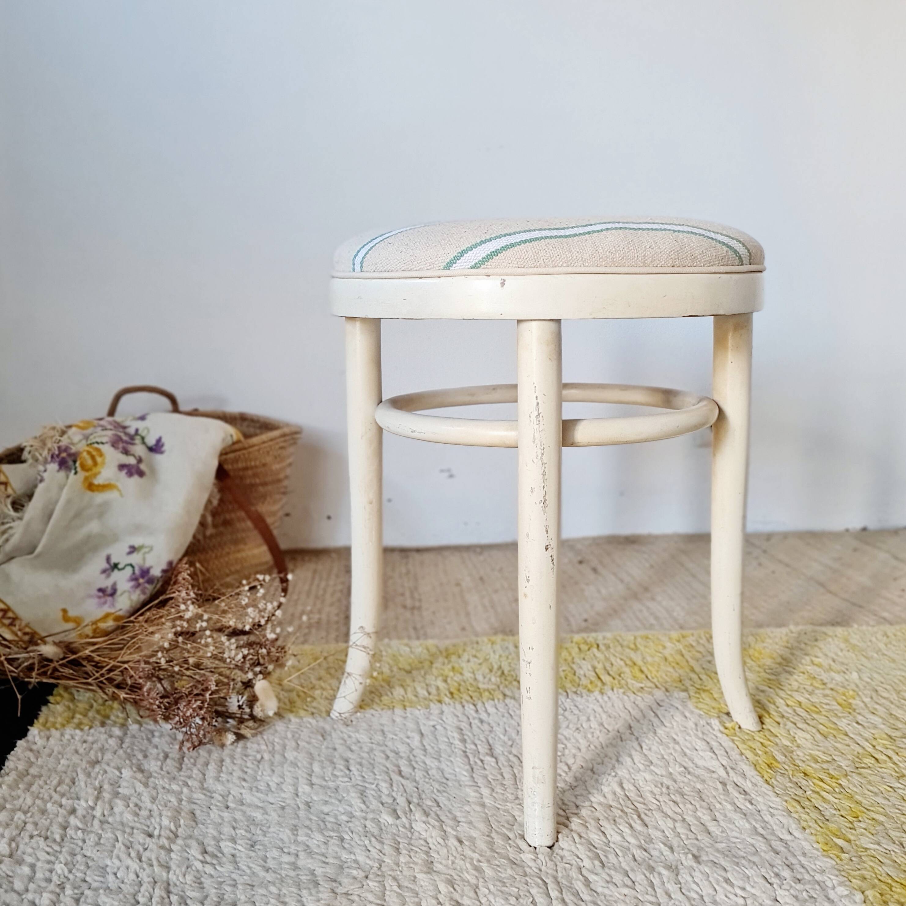 Antique stool with a wooden frame and a cream and green striped fabric seat.