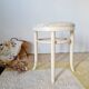 Antique stool with a wooden frame and a cream and green striped fabric seat.