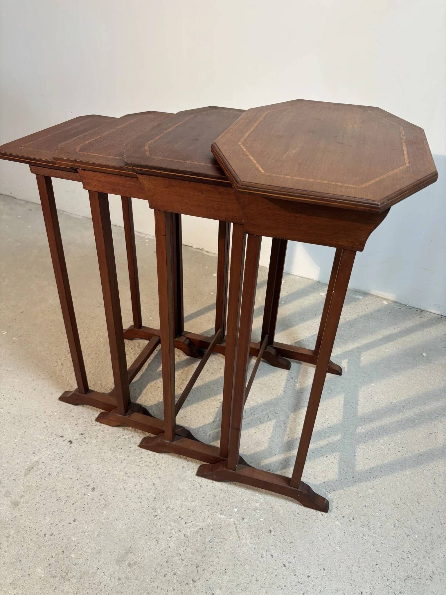 Four nesting tables with polygonal tops and decorative inlays.