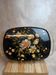 Large vintage 1960s platter with floral decoration on a black background and golden handles.