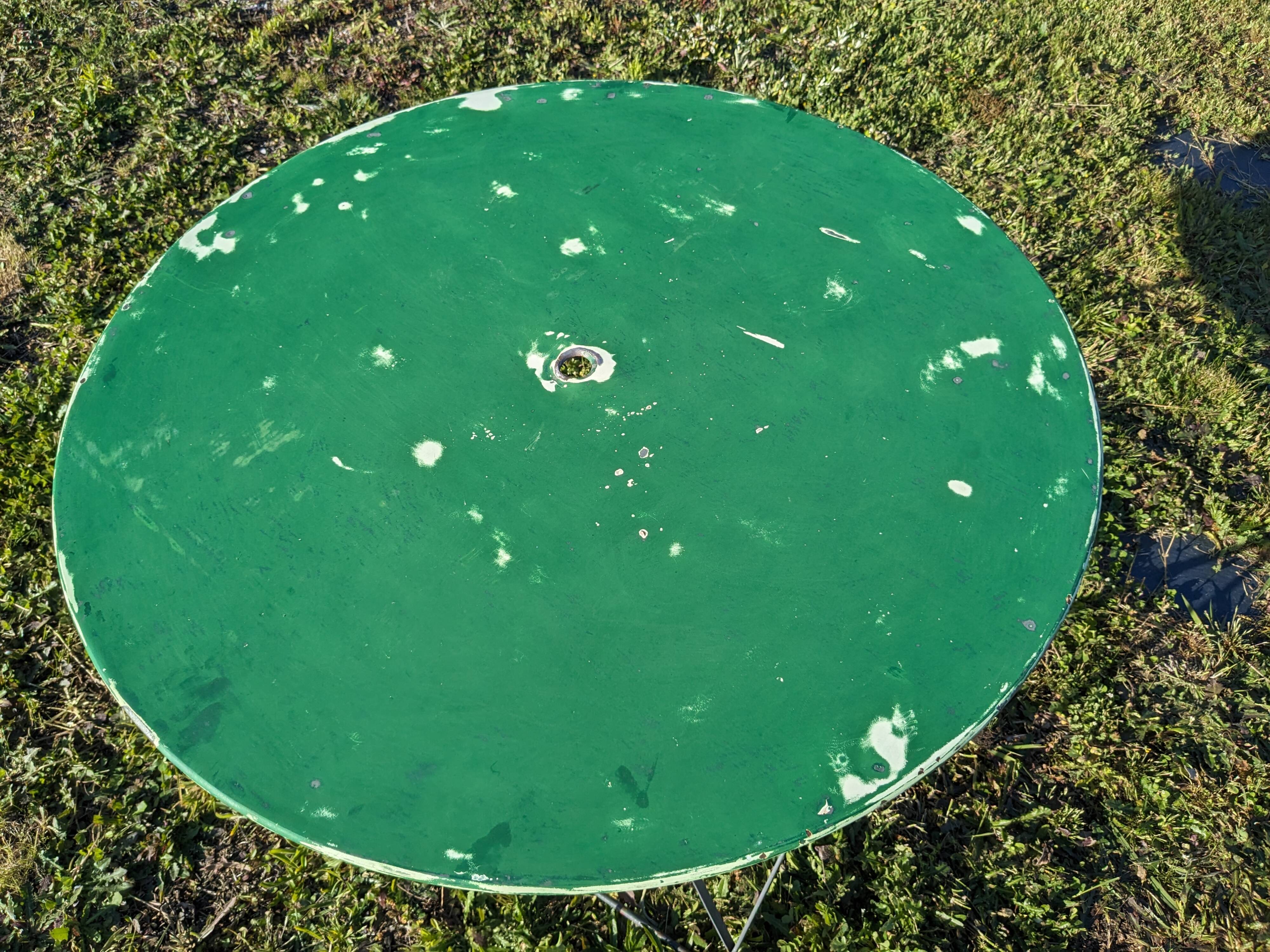 Antique round folding garden table with a green patina.