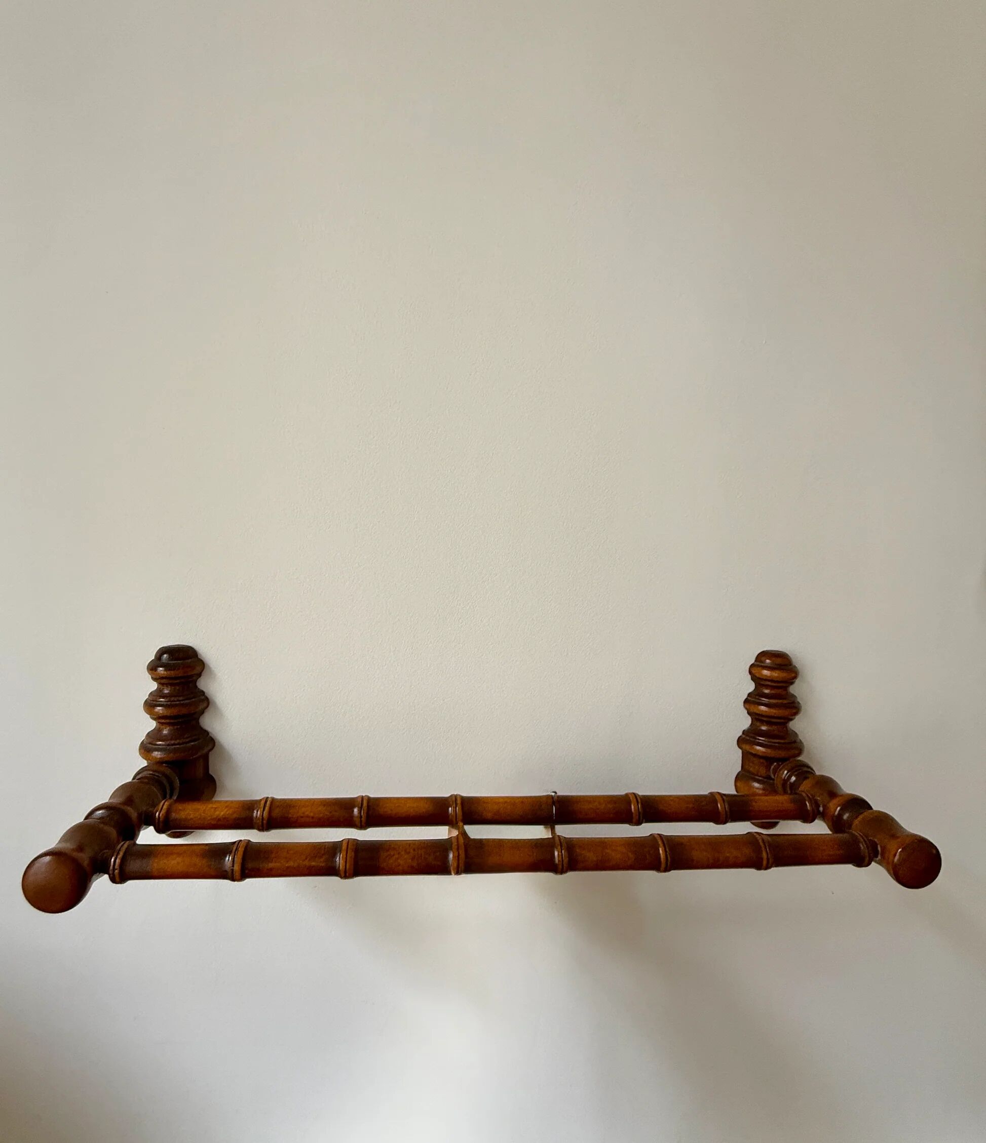 Wall-mounted coat rack made of turned wood in a bamboo style.