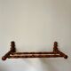 Wall-mounted coat rack made of turned wood in a bamboo style.