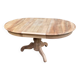 Round extendable dining table stripped in solid raw walnut with a central leg.
