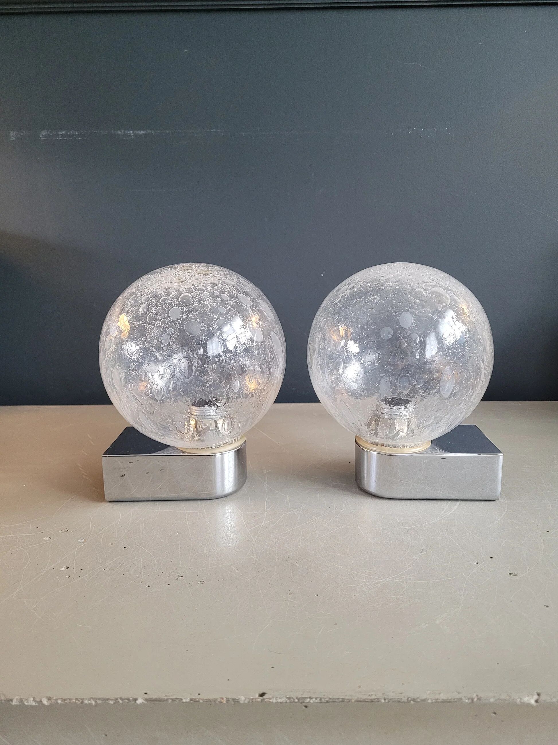 Pair of vintage wall lights in chrome metal with bubbled glass globes.