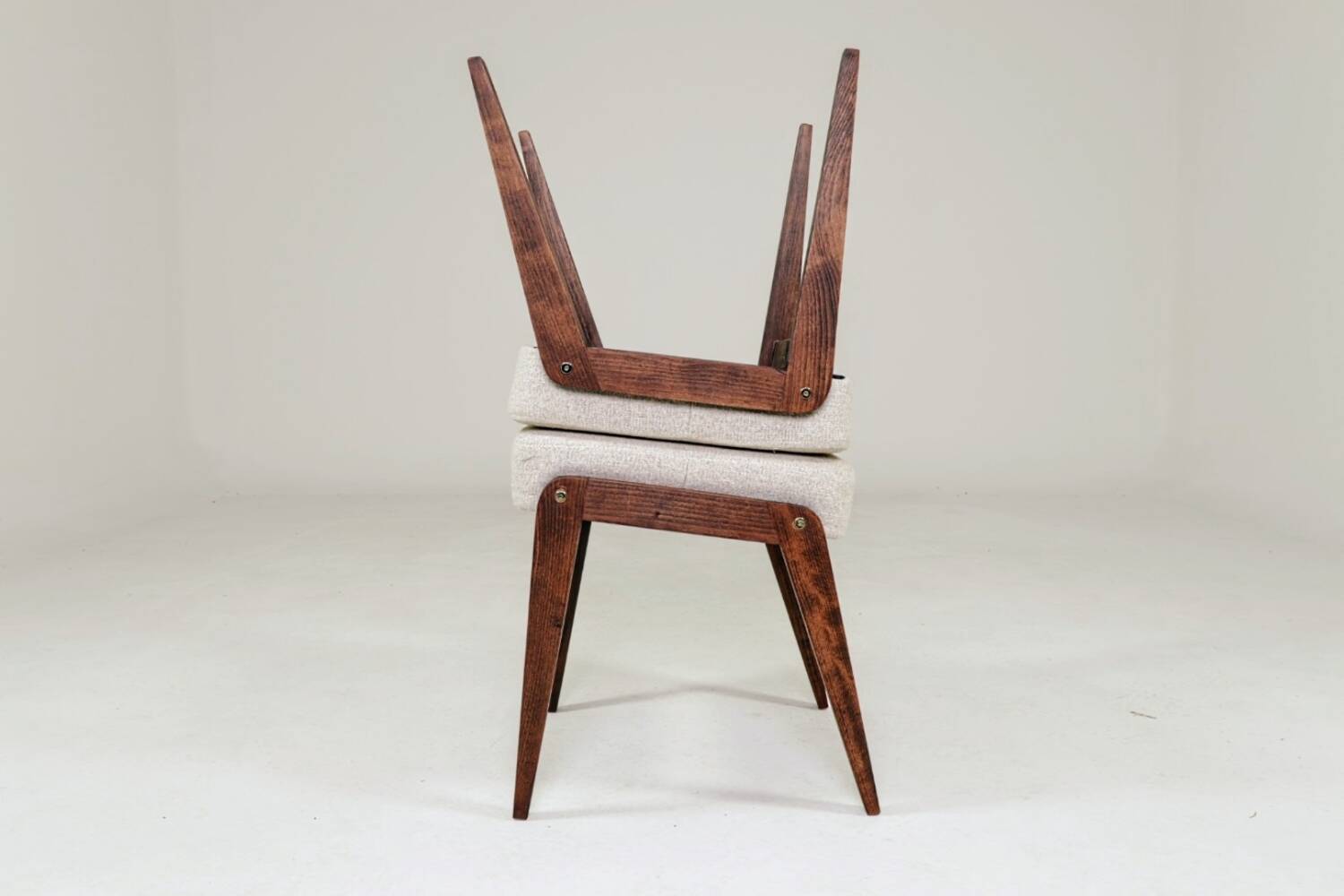 Pair of wooden stools with beige fabric.