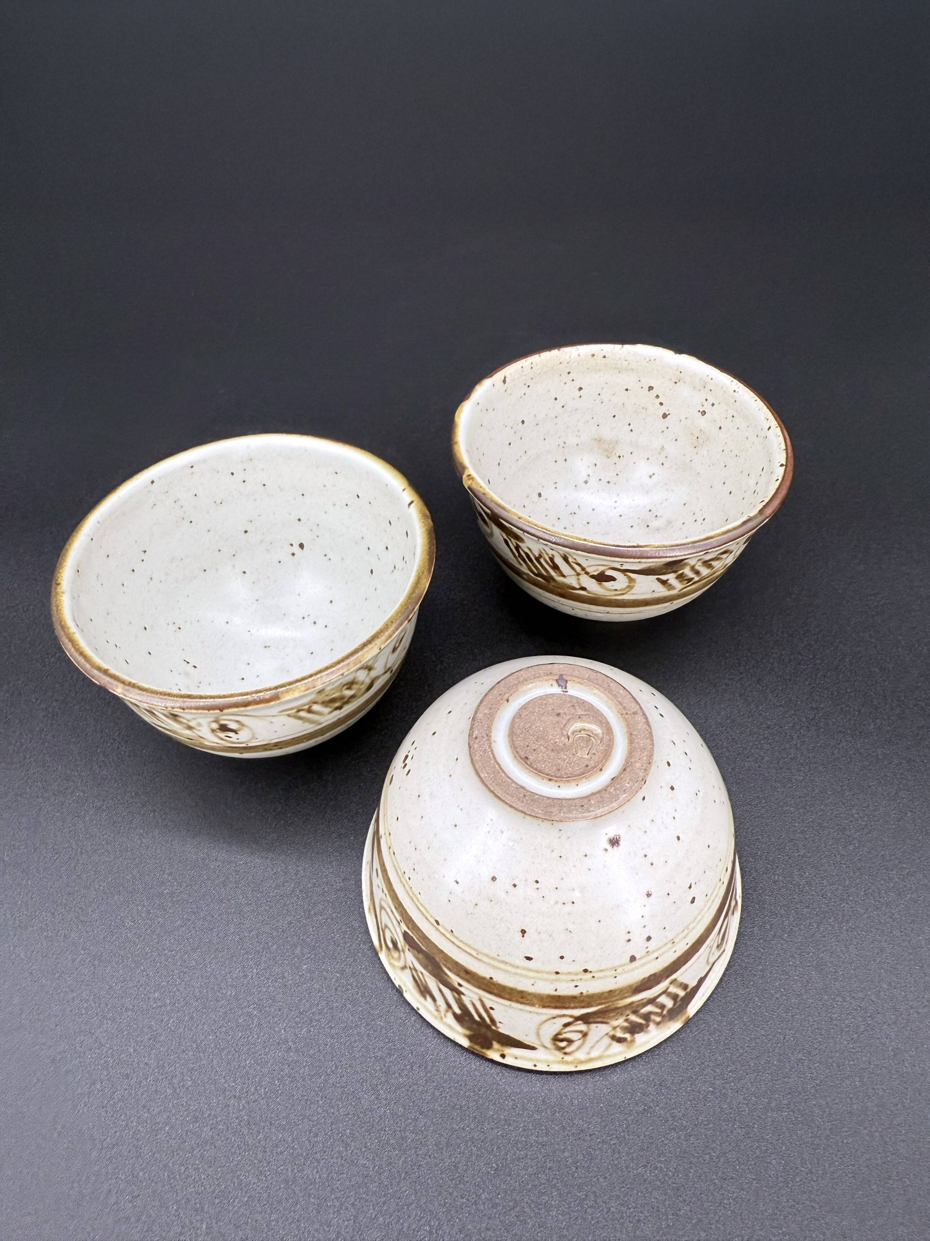 Trio of white speckled glazed stoneware bowls, gestural brown decoration – signed