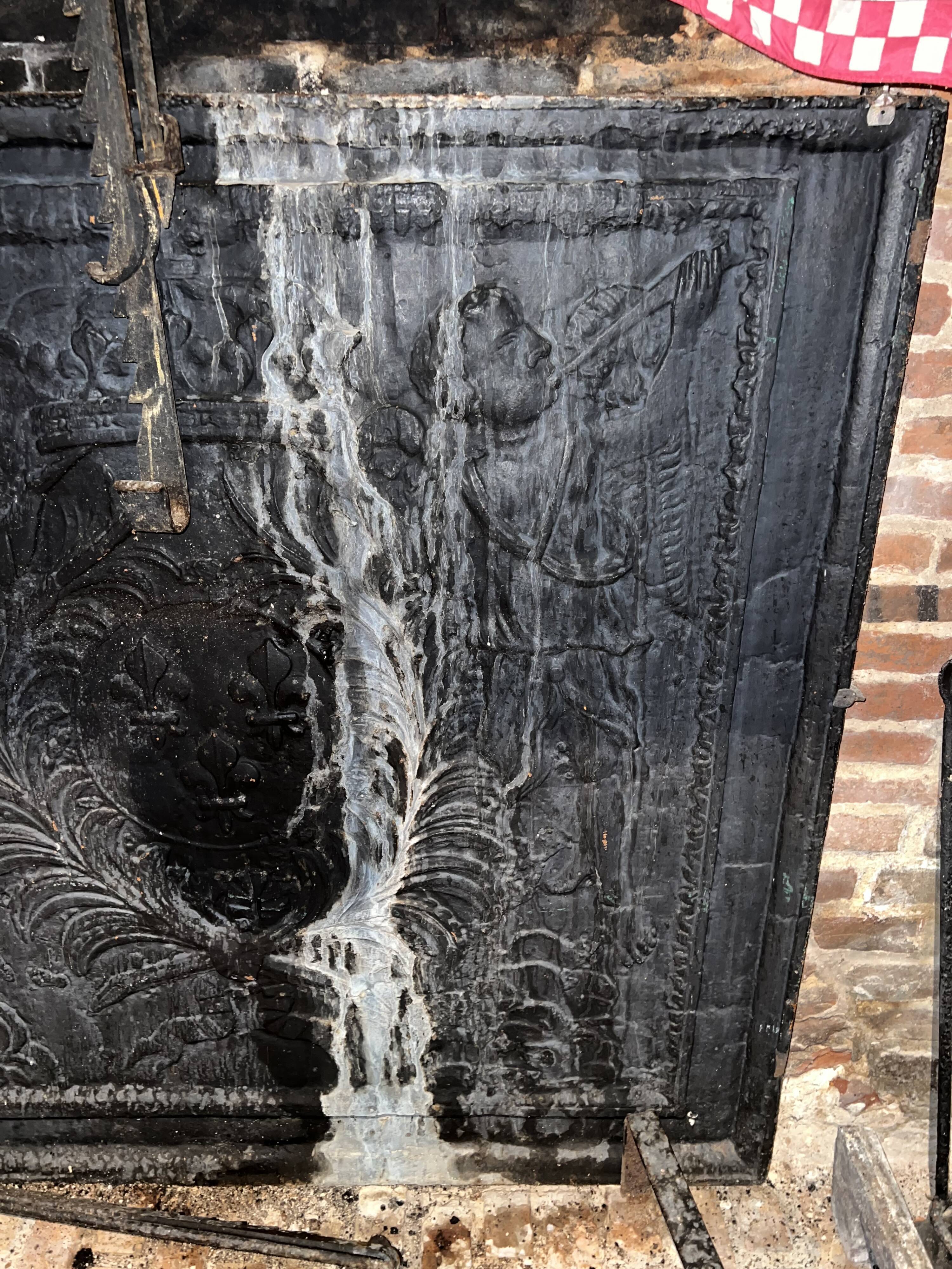 huge old fireplace plate has decoration of angels, crown and fleurs-de-lis