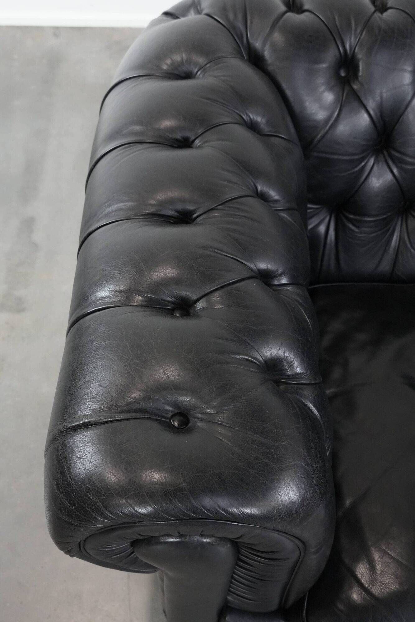 Set of a black cowhide leather Chesterfield armchair and matching ottoman