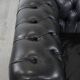 Set of a black cowhide leather Chesterfield armchair and matching ottoman