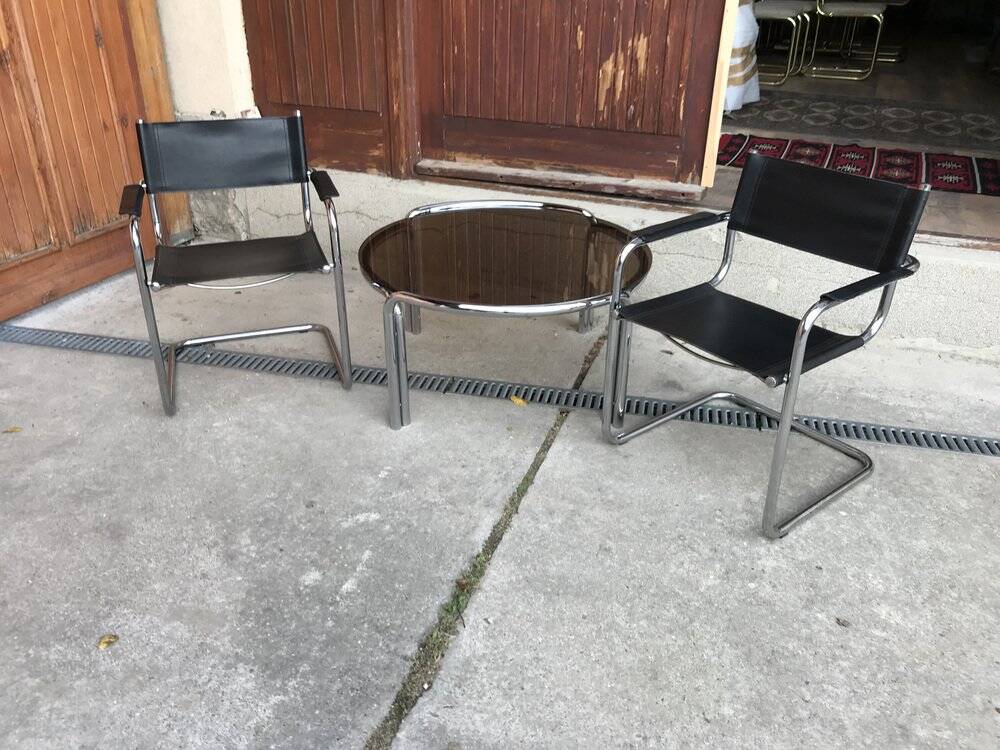 Mid-century round coffee table in chrome and smoked glass with 2 black leather chairs.