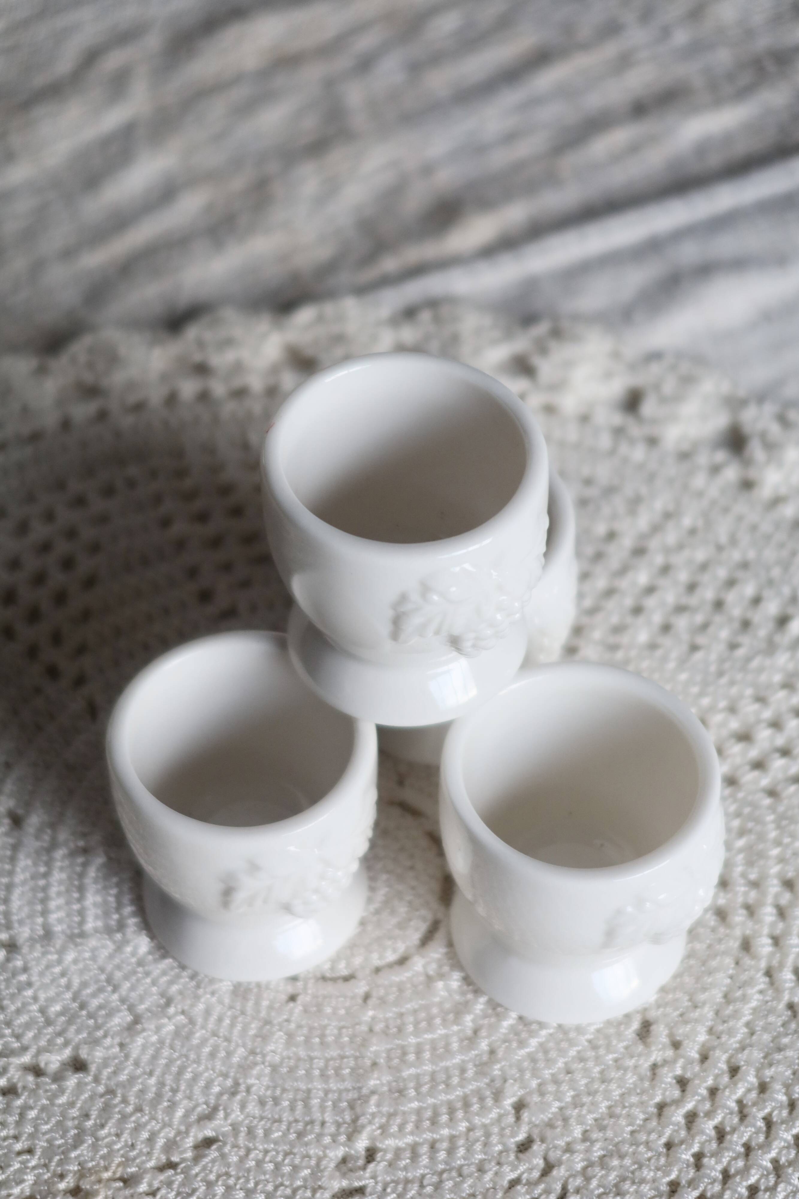 Vintage white porcelain egg cups with fruit motif.