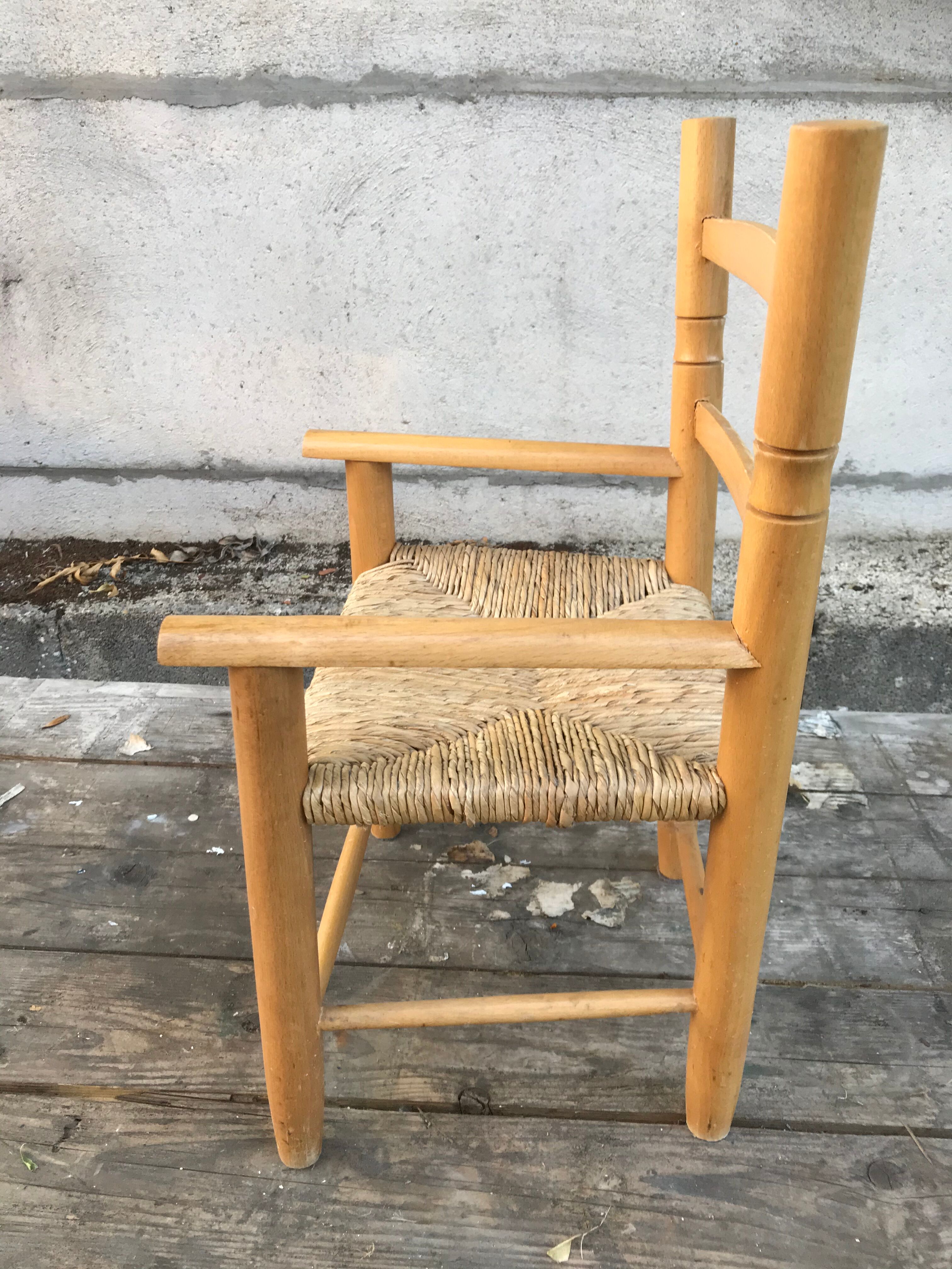 Old wooden children's armchair and vintage woven straw seat