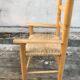 Old wooden children's armchair and vintage woven straw seat