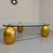 Vintage Italian design coffee table with a glass top and gold base, dating from the 1980s.