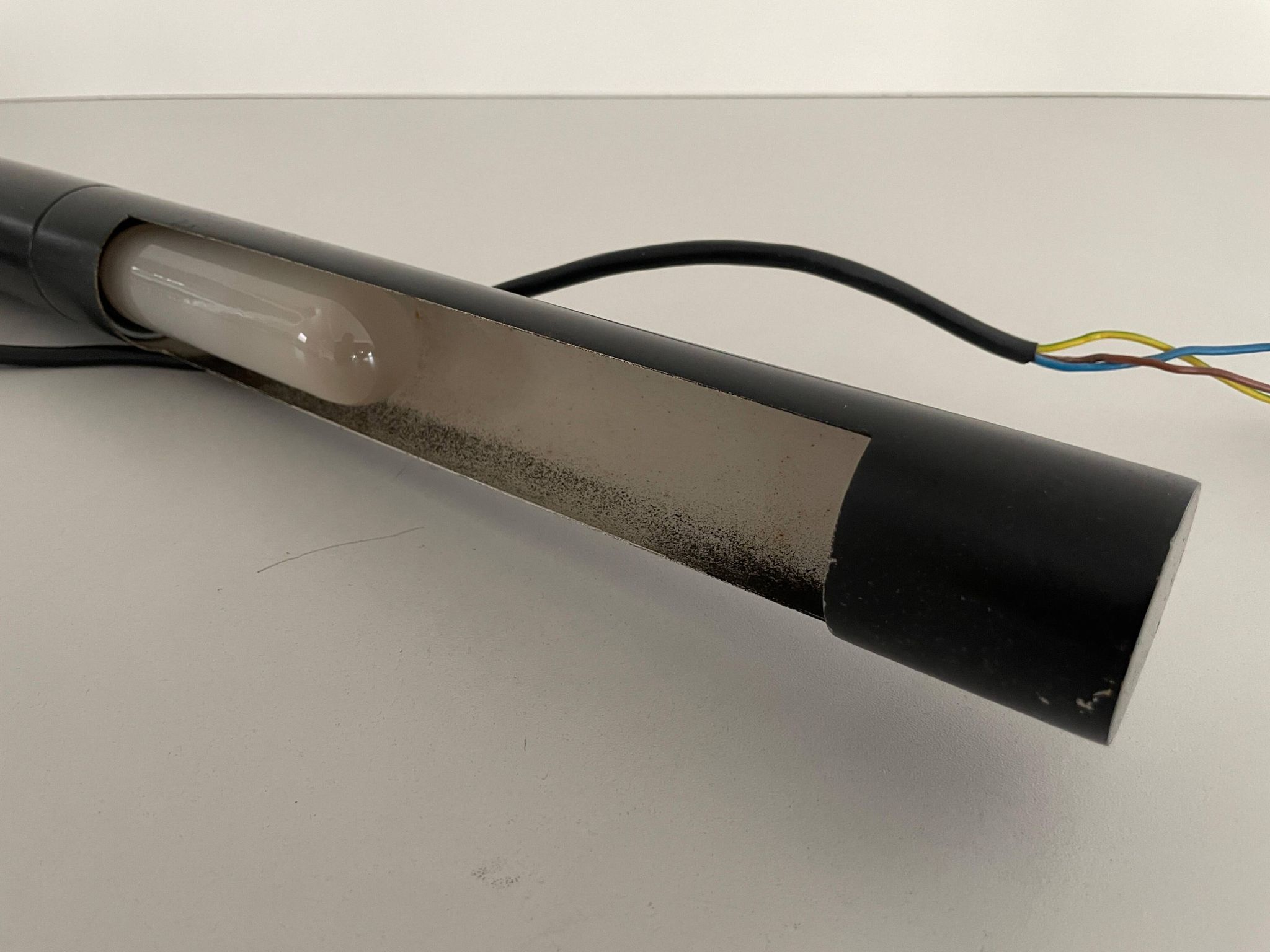 Minimalist black metal wall light with a cylindrical design, 1960s, Germany.
