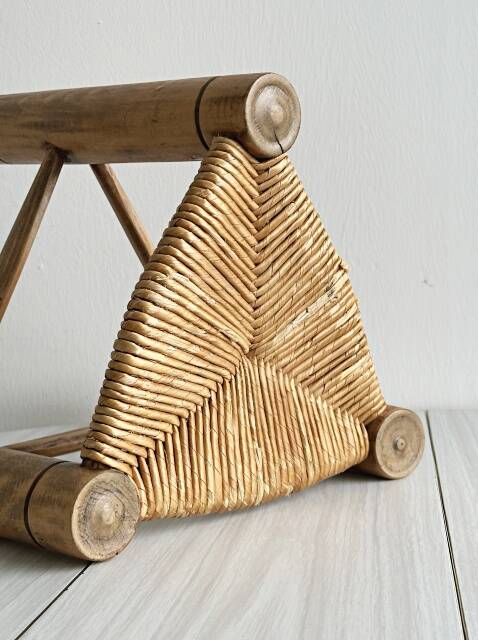 Antique tripod stool in light wood with a woven straw seat.