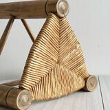 Antique tripod stool in light wood with a woven straw seat.