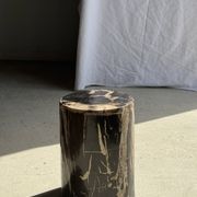 Black petrified wood side table with beige stripes and a semicircular shape.