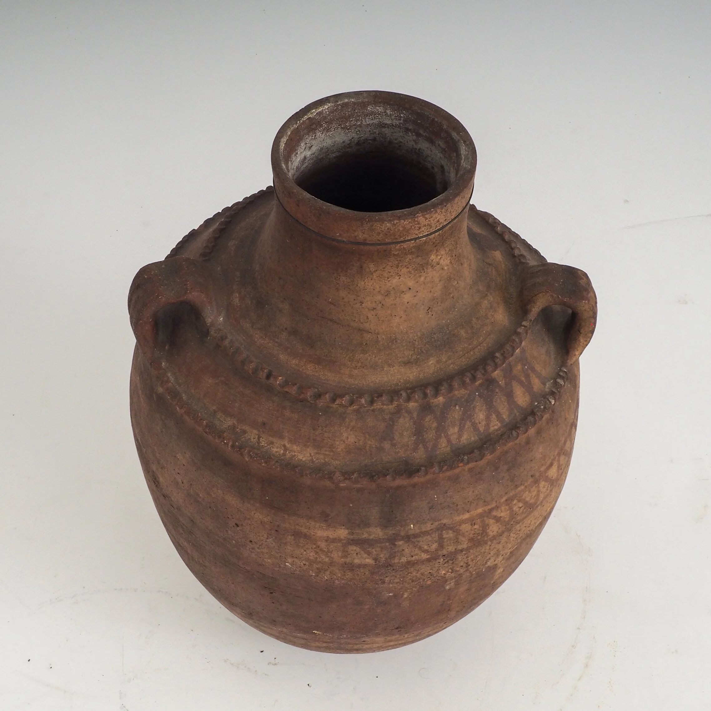 Vaisseau en terre cuite primitive avec des détails géométriques peints à la main.